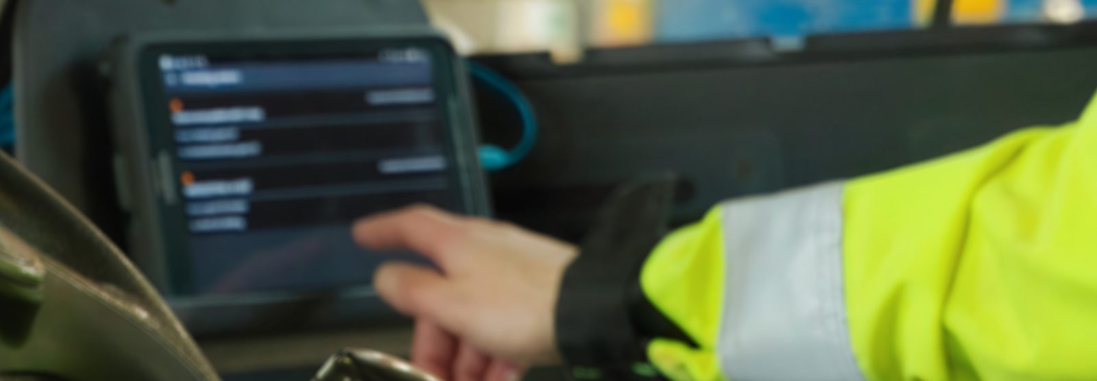 Close crop of an operator's hand tapping the job queue on a cab-mounted tablet